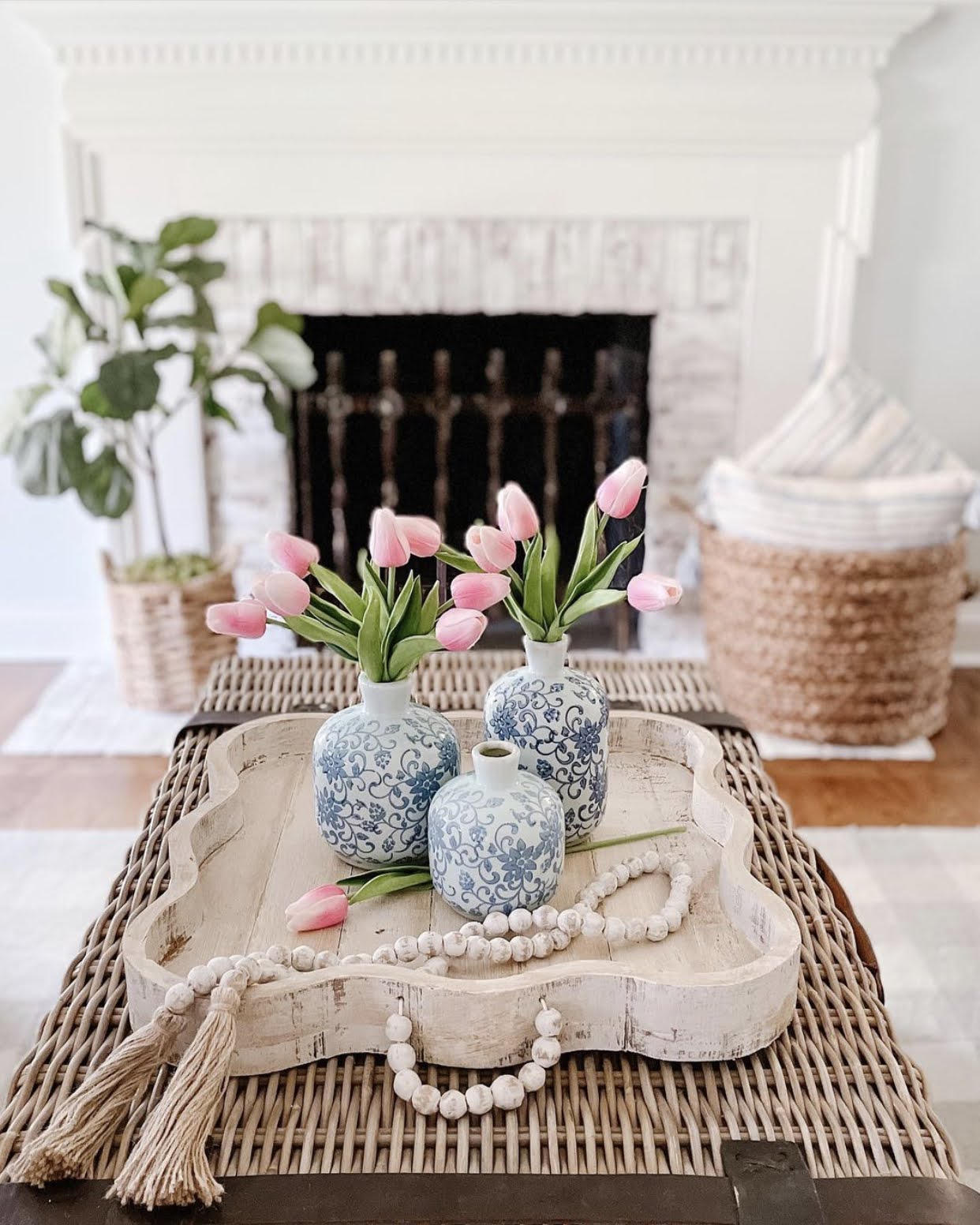 Table Decor blue and white 3 piece bud vases with pink tulips and a distressed table tray in front of beautiful white washed brick fireplace